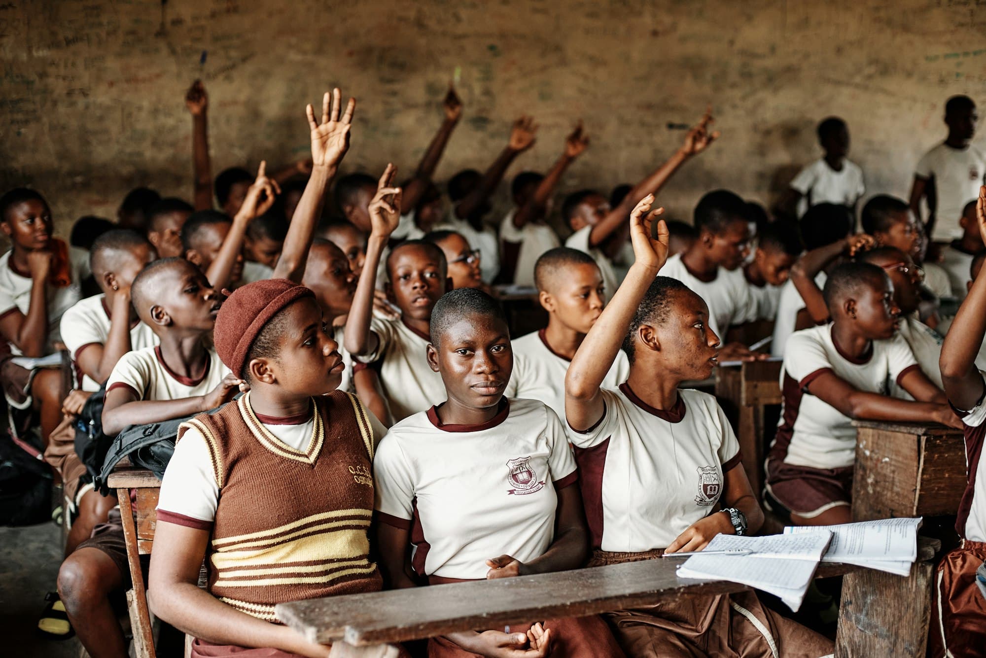 Secondary school students raising their hands to answer a question in class