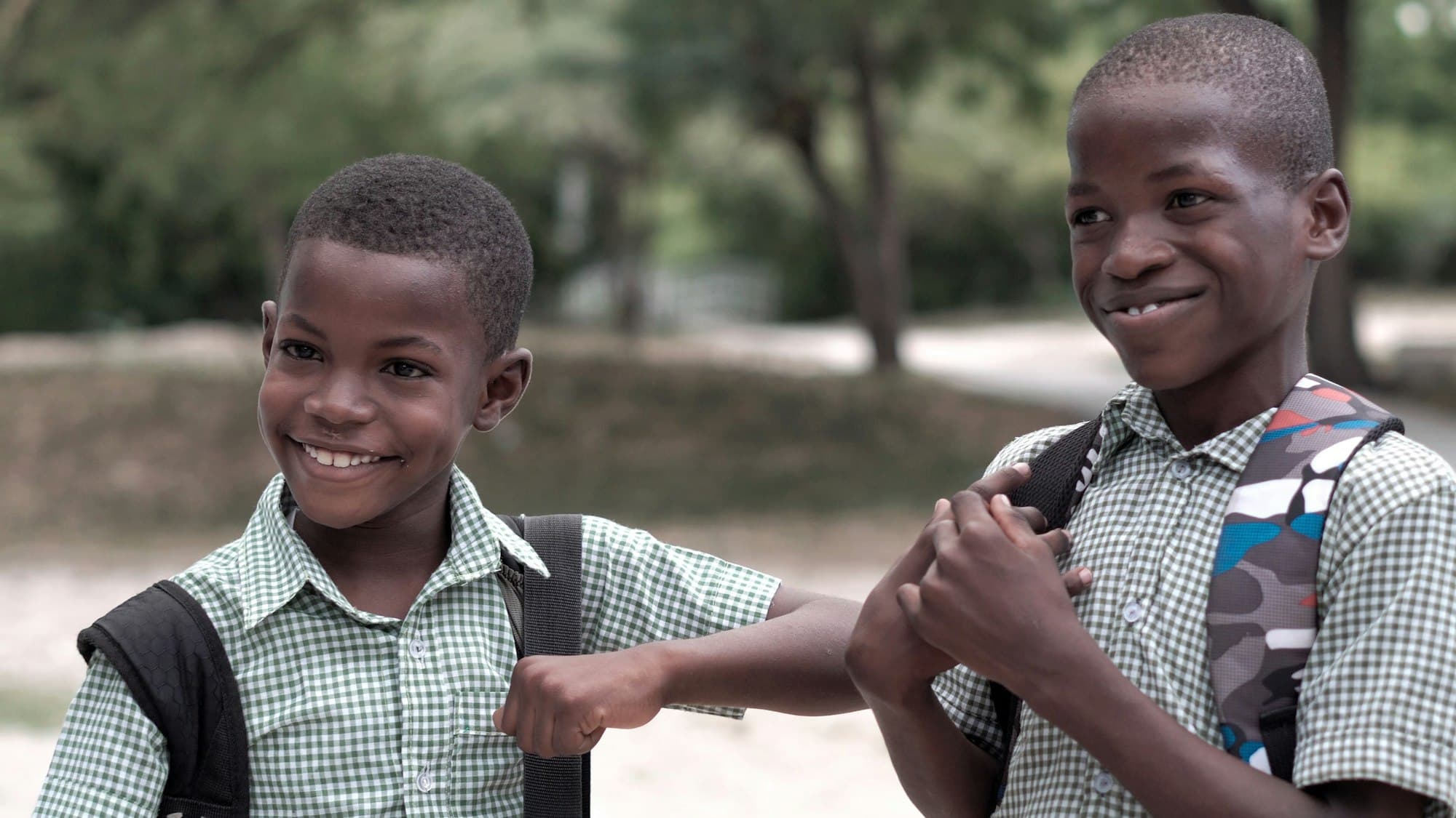 Two schoolboys with backpacks laughing together outdoors