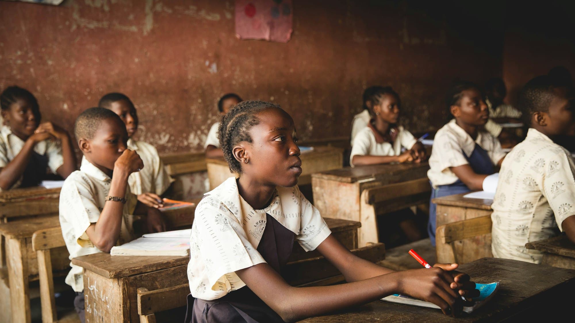 A schoolgirl listening attentively at her wooden desk